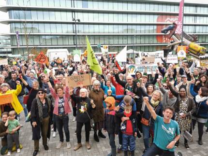 Een grote groep demonstranten staan voor het hoofdkantoor van ING in Amsterdam