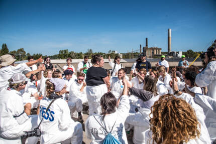 A large group of climate activists protests and puts their fists in the air in front of a coal plant in New Hampshire.